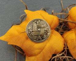 Kleine Wikinger Fibel mit Schildknoten aus Bronze auf einem Blatt